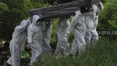 Petugas mengusung peti berisi jenazah yang meninggal dunia karena Covid-19 untuk dimakamkan di TPU Srengseng Sawah, Jakarta Selatan, Jumat (15/1/2021). [Suara.com/Angga Budhiyanto]