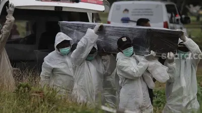 Petugas mengusung peti jenazah yang meninggal dunia karena Covid-19 untuk dimakamkan di TPU Srengseng Sawah, Jakarta, Jumat (15/1/2021). [Suara.com/Angga Budhiyanto]