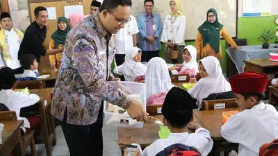 Gubernur DKI Jakarta Anies Baswedan membagikan makanan kepada siswa SD dalam Program Penyediaan Makanan Tambahan Anak Sekolah/Dokumentasi Pemprov DKI