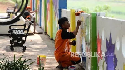 Petugas PPSU kelurahan Pondok Bambu membuat mural di tembok halte sepeda kawasan Banjir Kanal Timur (BKT), Jakarta, Rabu (20/11). (Foto: Republika/Prayogi)