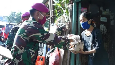 Prajurit TNI membagikan nasi bungkus dari rumah ke rumah warga di Kelurahan Baru, Tebet, Jakarta Selatan, Rabu (22/4/2020). (Puspen TNI)