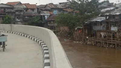 Warga melintas di samping Sungai Ciliwung, Jakarta, Rabu (19/9). [Suara.com/Muhaimin A Untung]