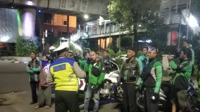 Petugas polisi mengimbau sekelompok pengemudi ojek online yang masih berkumpul pada dini hari di kawasan Blok M, Jakarta Selatan, untuk membubarkan diri demi mencegah penularan COVID-19. (Twitter @TMCPoldaMetro)
