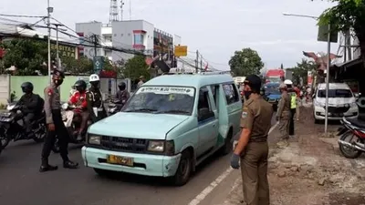 Petugas gabungan saat memeriksa pengendara di Check Point PSBB Pasar Rebo, Jaktim. (Suara.com/Bagaskara).