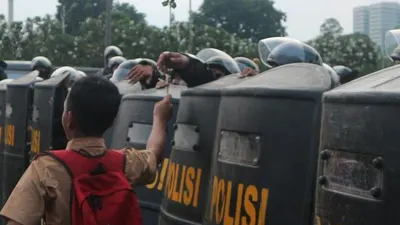 Seorang pelajar memberikan setangkai bunga untuk aparat kepolisian di seberang Gedung DPR RI, Jakarta, Rabu (25/9/2019)/Antara