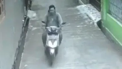 Pelaku yang mengendarai motor terekam CCTV saat melakukan pelecehan seksual terhadap seorang perempuan berkerudung panjang yang sedang berjalan kaki. (Instagram/Tribunnews)