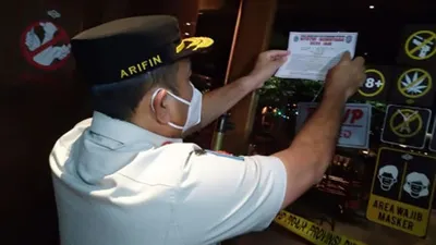 petugas sedang memberikan tanda pelanggaran suatu tempat terhadap protokol kesehatan Covid-19 di Jakarta / beritajakarta.id