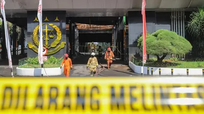 Petugas Damkar DKI berjalan keluar usai melakukan proses pendinginan di Gedung Utama Kejaksaan Agung RI di Jalan Sultan Hasanuddin, Jakarta Selatan, Minggu (23/8). [Suara.com/Alfian Winanto]