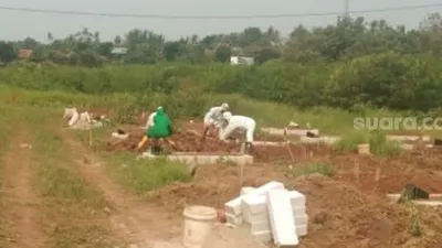 Para penggali kubur di TPU Buniayu, Kecamatan Sukamulya, Kabupaten Tangerang, tengah memakamkan jenazah Covid-19. [Suara.com/Ridsha Vimanda Nasution]