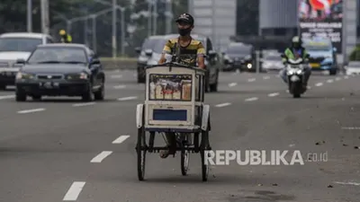 Pedagang menggunakan masker saat melintasi kawasan Sudirman, Jakarta,Ahad (11/10). Pemerintah Provinsi DKI Jakarta mengurangi kebijakan rem darurat di Ibu Kota dengan kembali memberlakukan Pembatasan Sosial Berskala Besar (PSBB) Transisi mulai Senin (12/10) hingga Senin (25/10). Republika/Putra M. Akbar