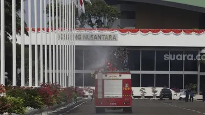 Petugas pemadam kebakaran menyemprotkan cairan disinfektan di area komplek Gedung DPR/MPR RI, Jakarta, Minggu (9/8/2020). [Suara.com/Angga Budhiyanto]