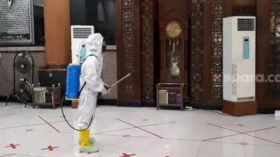 Petugas berpakaian APD lengkap saat menyemprot disinfektan di Masjid Agung Al Barkah Kota Bekasi. (Suaracom/Bagaskara).