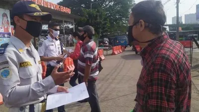Petugas Dishub Kota Depok menanyakan kelengkapan surat untuk calon penumpang KRL di Stasiun Depok Baru, Rabu (13/5/2020). (Suara.com/Supriyadi)