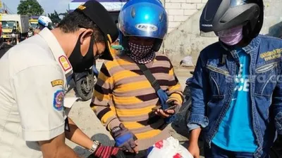 Petugas Dishub saat memeriksa SIKM terhadap pengendara motor di kawasan Pasar Rebo, Jaktim. (Suara.com/Bagaskara).