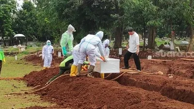 Penampakan petugas memakamkan jenazah pasien Corona di TPU Bambu Apus. (Suara.com/Bagaskara)