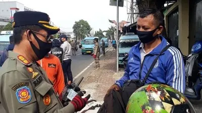 Petugas saat memeriksa SIKM dan KTP pengendara di check point PSBB Pasar Rebo, Jaktim. (Suara.com/Bagaskara).