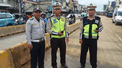 Petugas polisi lalu lintas dan Dinas Perhubungan berfoto di ruas Jalan Jatinegara Barat yang sebelumnya terendam banjir hingga tak bisa dilalui kendaraan. (Twitter @TMCPoldaMetro)