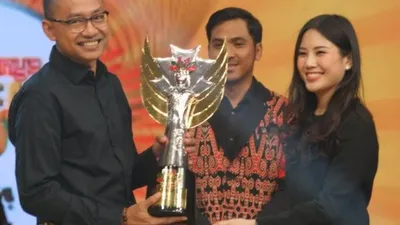 Wakil Menteri Pariwisata dan Ekonomi Kreatif, Angela Tanoesoedibjo, menyerahkan penghargaan kepada Kepala Bidang Seni Budaya Dinas Pariwisata dan Kebudayaan Provinsi DKI Jakarta Gumilar Ekalaya pada Minggu 17 November 2019  (iNews.id/Vien Dimyati)
