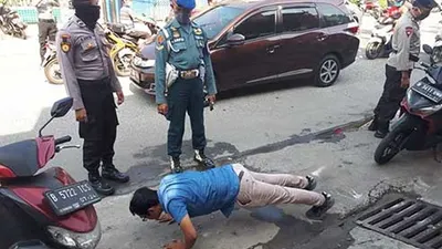 Seorang pelanggar dihukum push-up oleh petugas saat patroli gabungan Pembatasan Sosial Berskala Besar (PSBB), Selasa (14/4/2020). (dok Dispen Lantamal III)