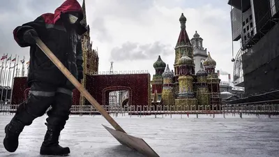 Seorang pekerja menggunakan masker medis membersihkan salju di depan replika Katedral St Basil di Moskow, 7 Februari 2020. AFP via Getty Images/Alexander Nemenov
