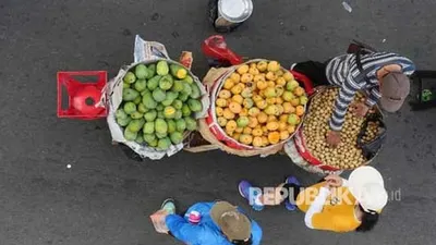 Seorang pedagang buah melayani konsumennya saat akan membeli dagangannya di Jl Thamrin Jakarta, Ahad (9/7), saat diberlakukannya waktu Car Free Day (CFD). Foto: Republika/Darmawan