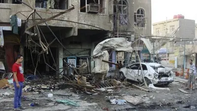 Warga menyaksikan bangunan dan mobil yang hancur akibat terkena serangan bom yang terus melanda Irak. Reuters