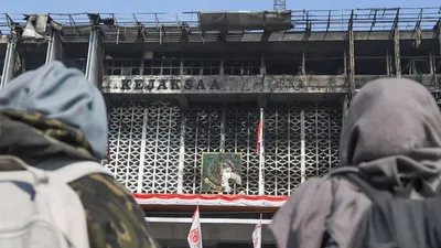 Dua orang warga melihat gedung utama Kejaksaan Agung RI yang habis terbakar di Jalan Sultan Hasanuddin, Jakarta Selatan, Minggu (23/8). [Suara.com/Alfian Winanto]