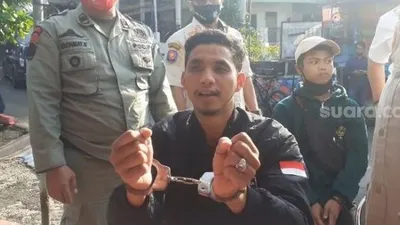 Seorang pengendara roda dua bernama Andi Albar saat memperlihatkan tangannya di borgol karena tidak mengguna masker di Jalan Raya Puncak Bogor Jawa Barat. (Suara.com/Andi Ahmad Sulaendi).