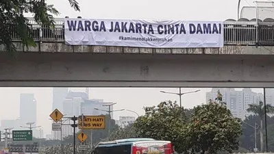 Sebuah spanduk terpasang di JPO depan Gedung DPR/Tribun