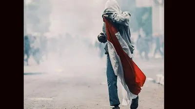 Foto viral pelajar SMA memegang bendera merah putih di tengah kepungan kabut asap gas airmata yang ditembakkan aparat/Media Sosial