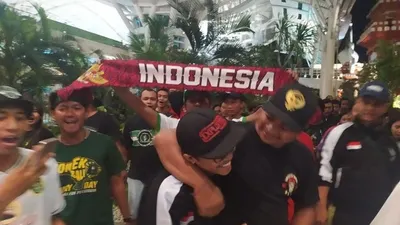 Suporter Indonesia, Andreas Setiawan (dirangkul), yang sempat ditahan Polisi Malaysia terkait komentar di media sosial yang dicurigai sebagai teror, tiba di Bandara Internasional I Gusti Ngurah Rai, Bali, Jumat malam (29/11/2019). (Kumparan.com)