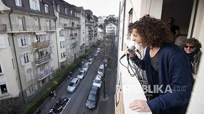 Penyanyi berkebangsaan Swiss Amandine (Rapin) melakukan konser singkat di balkonnya saat diberlakukannya keadaan darurat wabah penyakit corona di Lausanne, Swiss, Sabtu (28/3). (Foto: EPA-EFE/LAURENT GILLIERON)
