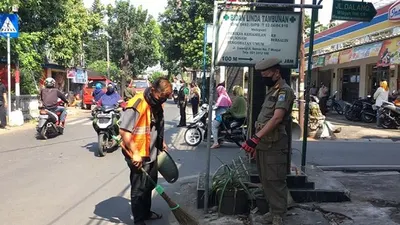 Salah satu warga di Kecamatan Cipayung sedang menjalani sanksi sosial menyapu jalan akibat tak memakai masker/dok: timur.jakarta.go.id