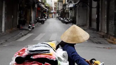 Seorang penjual berjalan melewati jalan sepi di tengah kekhawatiran tentang penyebaran Virus Corona COVID-19 di Hanoi Vietnam pada 26 Maret 2020. (Liputan6/Nhac Nguyen-AFP)