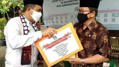 Wali Kota Jakarta Timur, Muhammad Anwar, memberikan apresiasi kepada salah satu perwakilan gugus tugas RW. (sumber: timur.jakarta.go.id)