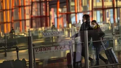 Pelancong memakai masker wajah di Bandara Internasional Beijing di China di tengah wabah virus corona (AP Photo/Mark Schiefelbein)
