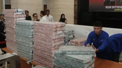 Petugas merapikan barang bukti uang saat ungkap kasus Tindak pidana korupsi dalam pengadaan BBM jenis High Speed Diesel (HSG) pada PT PLN Tahun Anggaran 2010 di Bareskrim, Mabes Polri, Jakarta, Jumat (28/6/2019). (ANTARA FOTO/Reno Esnir)