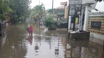 Seorang warga melintasi banjir yang melanda kawasan Rawalumbu, Bekasi Timur, Rabu (24/4/2019) petang, sementara sebuah kendaraan tampak terendam banjir. (Rangga Pandu/Antara Foto)