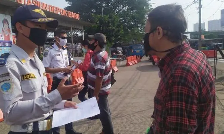 Petugas Dishub Kota Depok menanyakan kelengkapan surat untuk calon penumpang KRL di Stasiun Depok Baru, Rabu (13/5/2020). (Suara.com/Supriyadi)